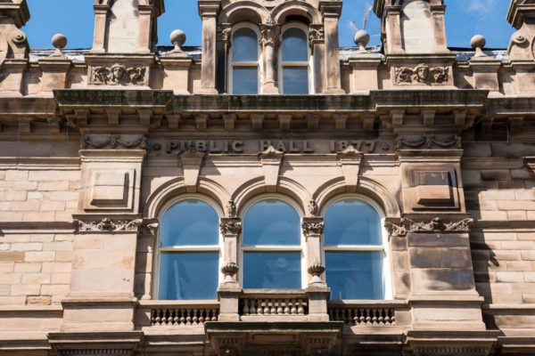 Original stone carvings on the front of the building, featuring a bust of Henry Harvey and the Twin Muses, Arts and Science either side.